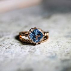 a blue diamond ring sitting on top of a stone