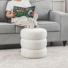 a person sitting on a couch reading a book and stacking it in front of them