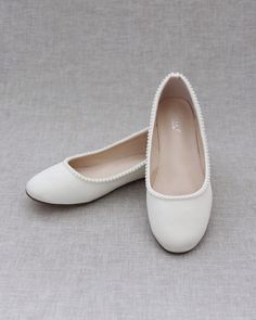 a pair of white women's shoes sitting on top of a gray cloth covered floor