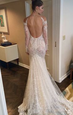 a woman in a wedding dress looking at herself in the mirror with her back to the camera