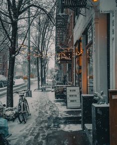 a bike parked on the side of a snowy street next to a building and trees