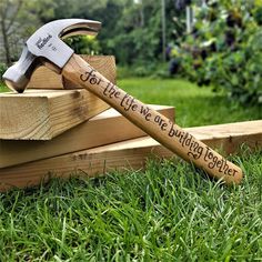 a hammer and some wooden blocks with writing on them sitting in the grass near trees