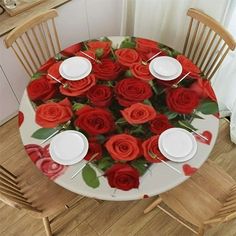 a white plate topped with red roses on top of a wooden table next to chairs