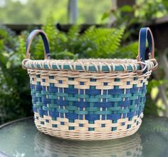 a blue and white basket sitting on top of a glass table next to green plants