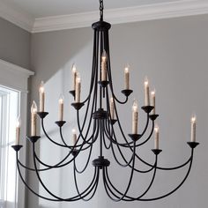 a black chandelier with candles hanging from it's sides in a room