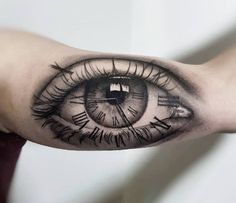 an eye tattoo on the arm with some sort of clock in it's center