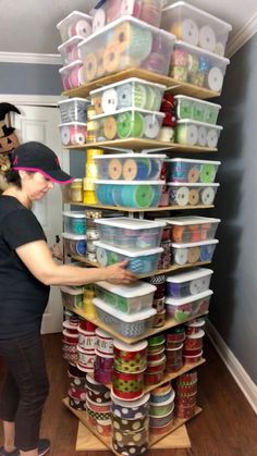 a woman standing next to a stack of plastic containers on top of a wooden floor