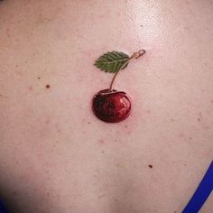 a small cherry on the back of a woman's shoulder