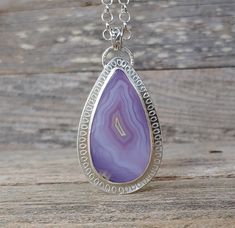 "Breathtaking Agua Nueva Agate sterling silver metalwork pendant necklace. The stone features the most amazingly vibrant shades of purple to lavender with a full fortification pattern. It has been hand stamped. This is a big statement pendant necklace that will surely get noticed! It comes with a substantial 5mm sterling silver rollo chain finished with a lobster claw clasp and amethyst briolette. The pendant measures 3\" long from the top of the bail and x 1 1/2\"W. The chain measures 18\" long Unique Purple Teardrop Jewelry, Handmade Lavender Teardrop Jewelry, Handmade Purple Teardrop Pendant Jewelry, Purple Teardrop Bohemian Necklace, Bohemian Purple Teardrop Necklace, Lavender Teardrop Natural Stones Jewelry, Purple Pendant Necklace, Silversmith Jewelry, Purple Pendant