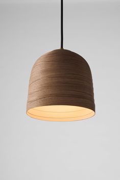 a light hanging from a ceiling with a wooden shade on it's side and a black cord in the middle