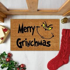 a christmas door mat with the words merry grinmas written on it next to stockings and presents