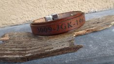 a brown leather bracelet with the word jack - 10 on it sitting on top of a piece of wood