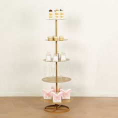 three tiered cake stand with cupcakes on top and pink bows around the edges