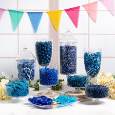 there are many blue and white candies in glass containers on the table next to each other