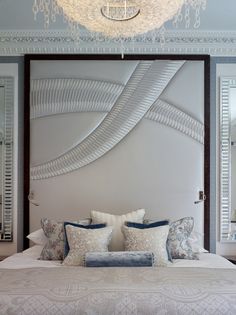 a bedroom with a large white headboard and chandelier hanging from the ceiling