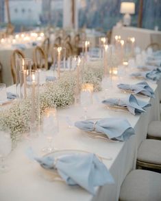 a long table is set with white and blue linen napkins, silverware, and baby's breath flowers