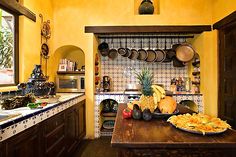 a kitchen with yellow walls and lots of cooking utensils hanging from the ceiling