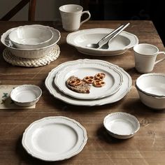 a table topped with white dishes and cups filled with pretzel cookies on top of them