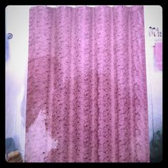 a pink shower curtain hanging on the side of a wall