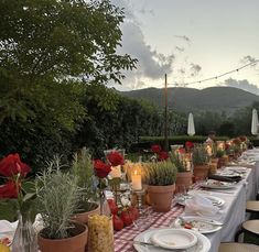 a long table is set up with plates and candles for an outdoor dinner party in the mountains