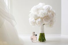 a bouquet of white flowers sitting next to a perfume bottle