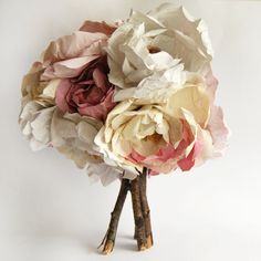 a bouquet of flowers sitting on top of a wooden stick in front of a white wall