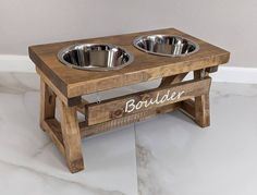 a wooden elevated dog bowl stand with two stainless steel bowls on it's legs