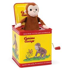 a stuffed monkey sitting on top of a yellow box with the caption curious george