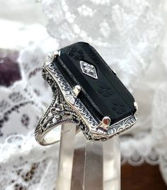 a black and white stone ring sitting on top of a metal stand with lace in the background