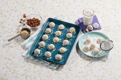 there are several desserts on the table with milk and nuts in bowls next to them