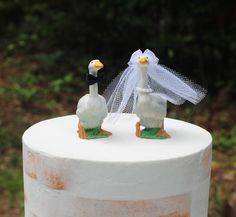 two ducks are standing on top of a wedding cake