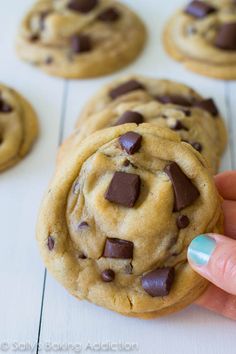 chocolate chip cookies are being held by a hand