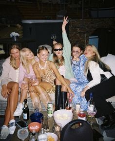 a group of women sitting next to each other on top of a couch with drinks