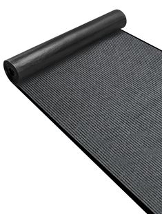 a roll of black carpet on top of a white surface with a rolled up mat