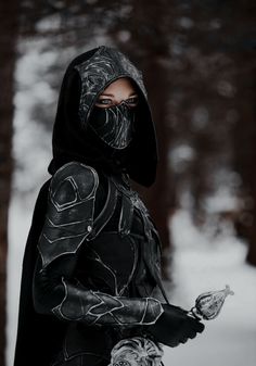 a woman wearing a hoodie and holding a knife in her hand while standing in the snow