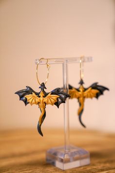 two dragon shaped earrings sitting on top of a wooden table