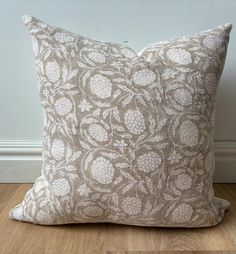 a brown and white pillow sitting on top of a wooden floor next to a wall