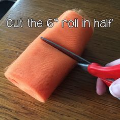 someone is cutting out the roll in half with scissors on a wooden table next to a pair of pink gloves