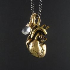 My Anatomical Heart necklace, beautifully detailed, cast in solid bronze and plated in 24 karat gold. A crystal clear quartz, beautifully faceted and skillfully wrapped in sterling silver gold filled wire. Sometimes I really wish I was a better photographer, to do this beauty the justice it deserves. The heart itself is as anatomically correct a heart as you'll find, lovingly detailed, meticulously crafted. Every artery and valve, every atrium and ventricle are captured in this pendant, and it h Unique Heart-shaped Gold Jewelry, Unique Gold Heart-shaped Jewelry, Unique Gold Heart Pendant Jewelry, Unique Gold Jewelry With Heart Charm, Silver Heart-shaped Brass Necklace, Spiritual Brass Heart Pendant Jewelry, Heart-shaped Spiritual Brass Jewelry, Spiritual Heart-shaped Brass Necklaces, Bronze Heart Pendant Jewelry With Heart Charm