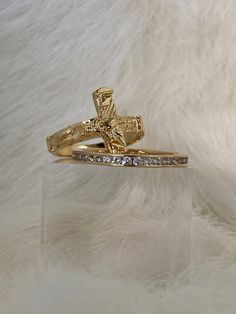 a gold ring with a cross on it and some diamonds in the middle, sitting on top of a white fur