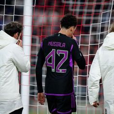 two soccer players standing next to each other in front of a goalie's net