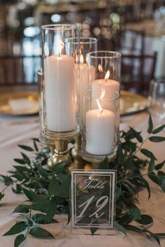 candles are lit on the table with greenery