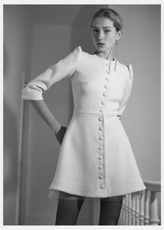 black and white photograph of a woman in a dress with buttons on the front, wearing tight stockings