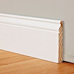 a close up view of the corner of a white skirting board on a wood floor