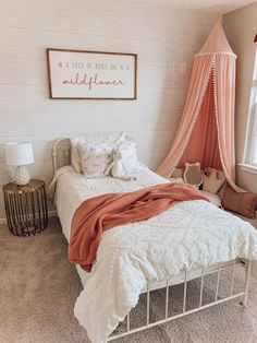 a white bed with a pink canopy over it and some pillows on the bottom side