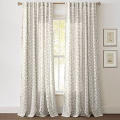 the curtains in this room are white and have floral designs on them, while the window is