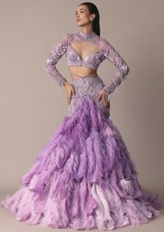 Immerse yourself in a world of ethereal elegance with our enchanted lavender purple trail lehenga set. This mesmerizing ensemble redefines sophistication with its captivating design and exquisite detailing. Crafted from luxurious net fabric the fish cut trail skirt lends an aura of grace and fluidity to every movement. Creating a mesmerizing silhouette the innovative 3D crystal and jewel embellishments on the blouse enhanced with feather detailing that is meticulously handcrafted to perfection will ensure you command attention. Dry clean only if required. Slight variation in color is possible due to digital photography. Luxury Designer Purple Dress, Luxury Festive Net Choli, Luxury Purple Corset Dress For Wedding, Luxury Elegant Purple Dresses, Luxury Wedding Lehenga With Tiered Skirt, Luxury Festive Net Dress, Luxury Purple Party Dress, Luxury Unstitched Purple Lehenga, Luxury Net Choli In Traditional Drape