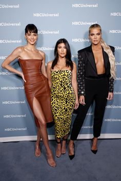 three women standing next to each other in front of a blue wall with the nbc universal logo on it