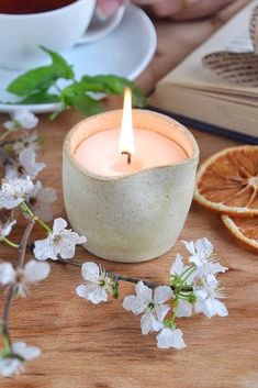 a candle that is sitting on a table next to some orange slices and teacups