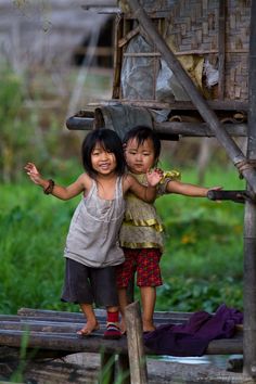 two children are standing in the rain with their arms around each other and one is holding an umbrella